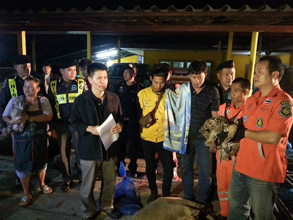 Two suspects line up with the confiscated animals